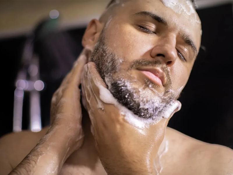Мужчина моет бороду